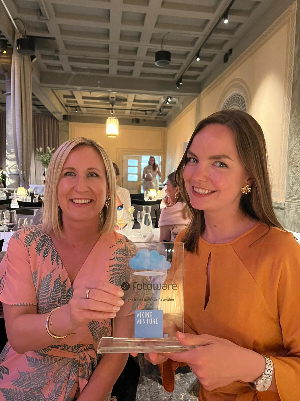 Two women smiling and holding an award