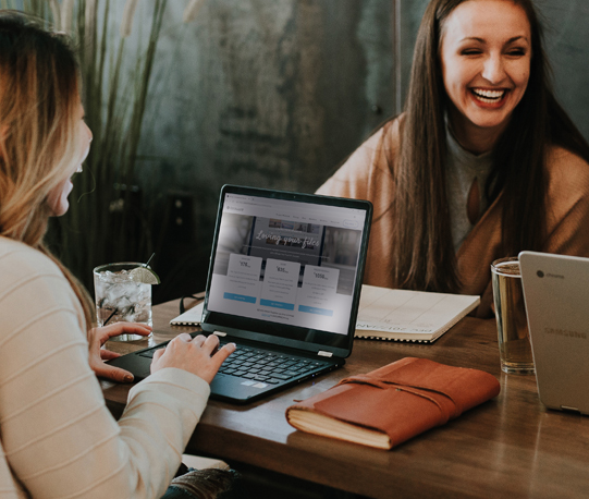 Two woman working on laptops smiling